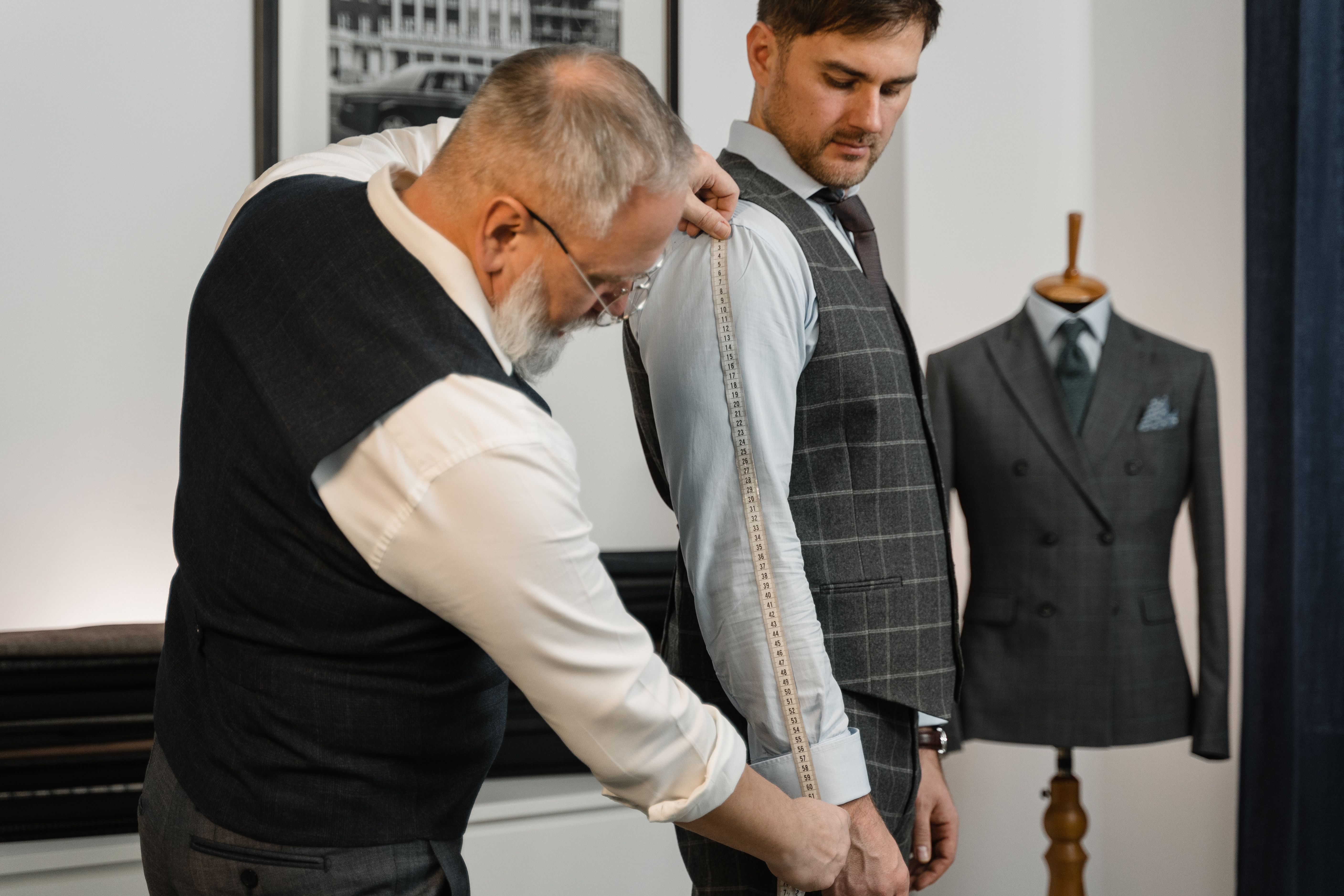 Professional tailor measuring a client for a bespoke suit in a modern atelier