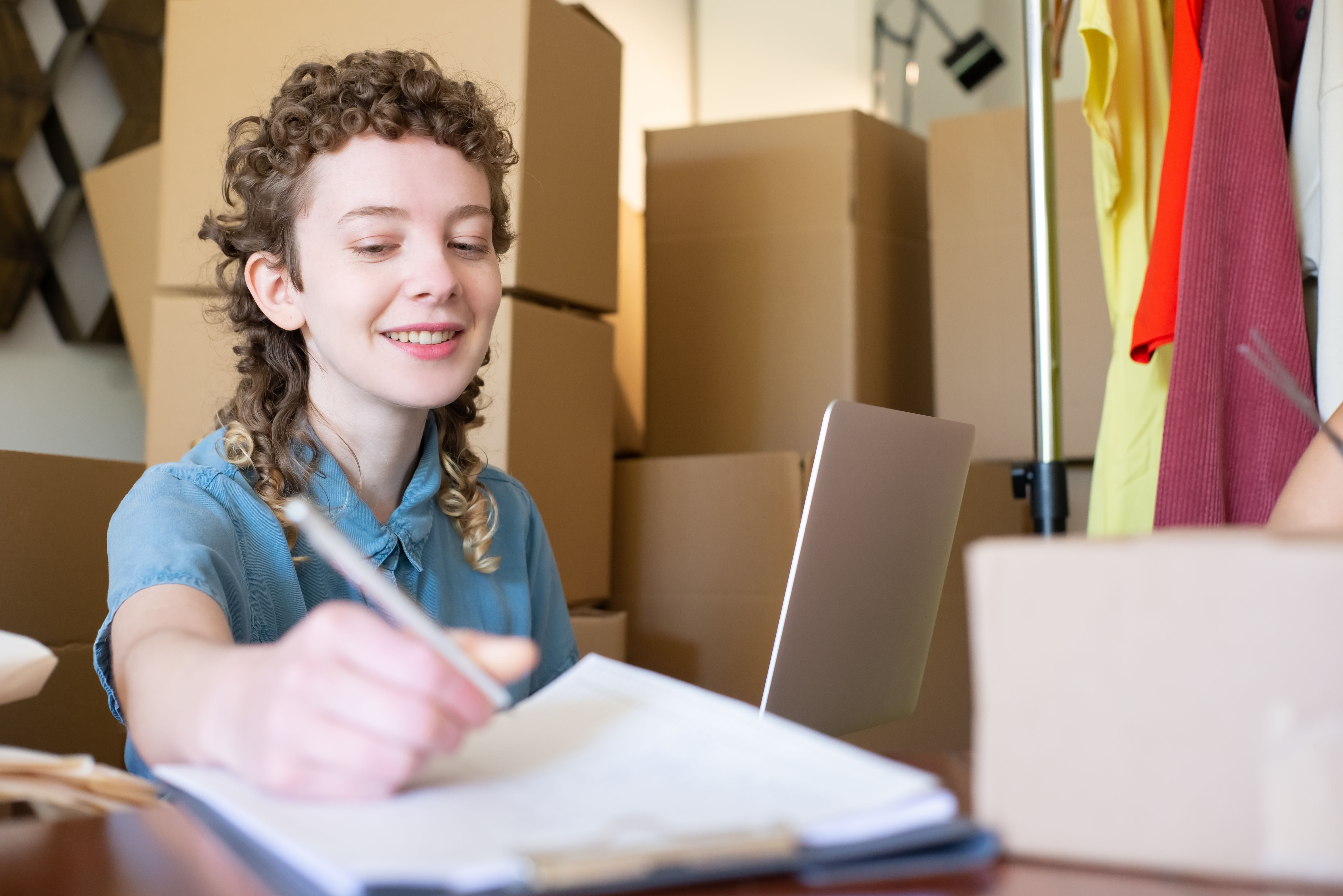 Smiling small business owner managing her shop with a laptop and packages, building an online presence
