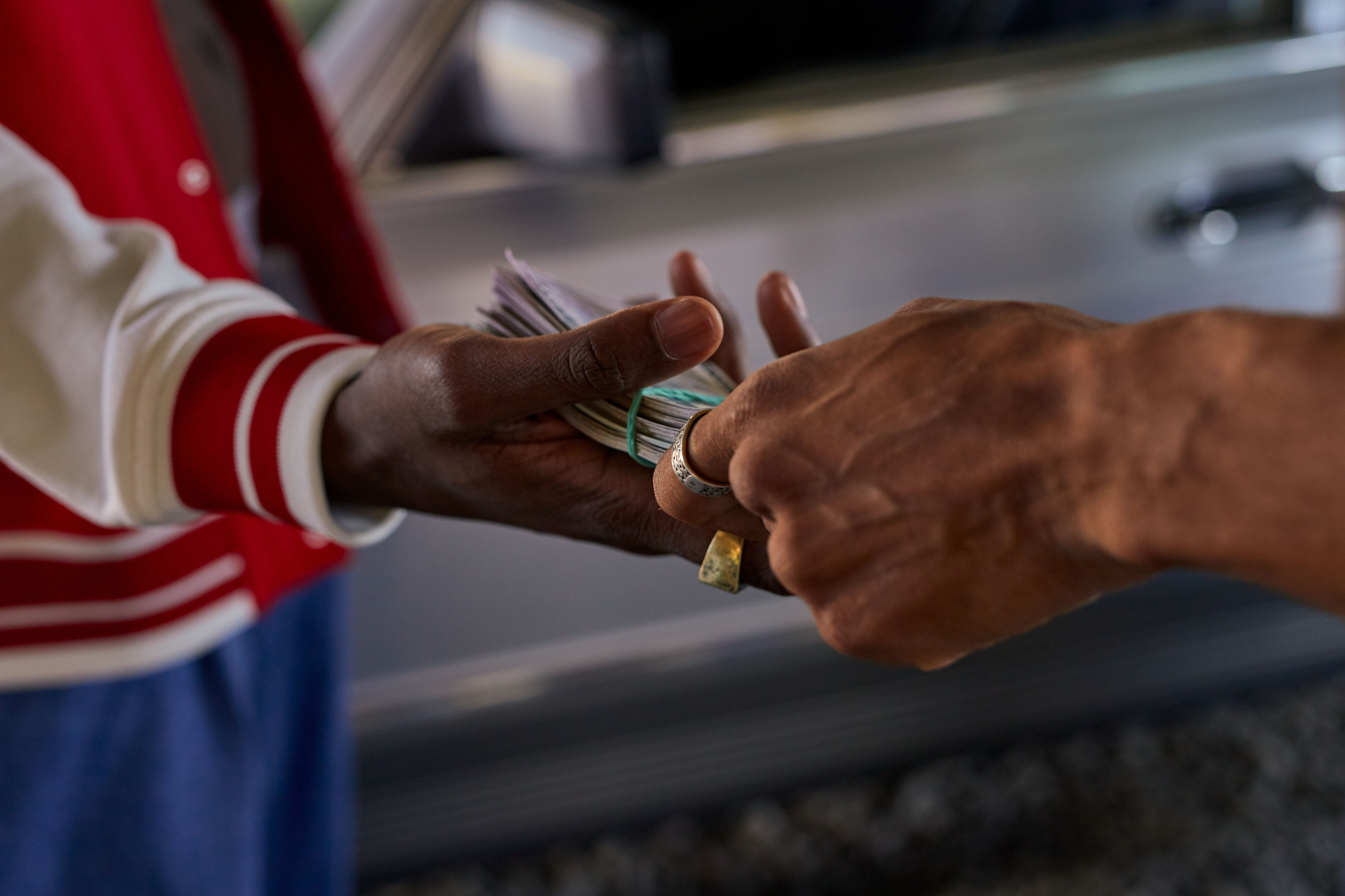Two hands exchanging a bundle of cash, representing the financial transaction behind third-party lawsuit funding