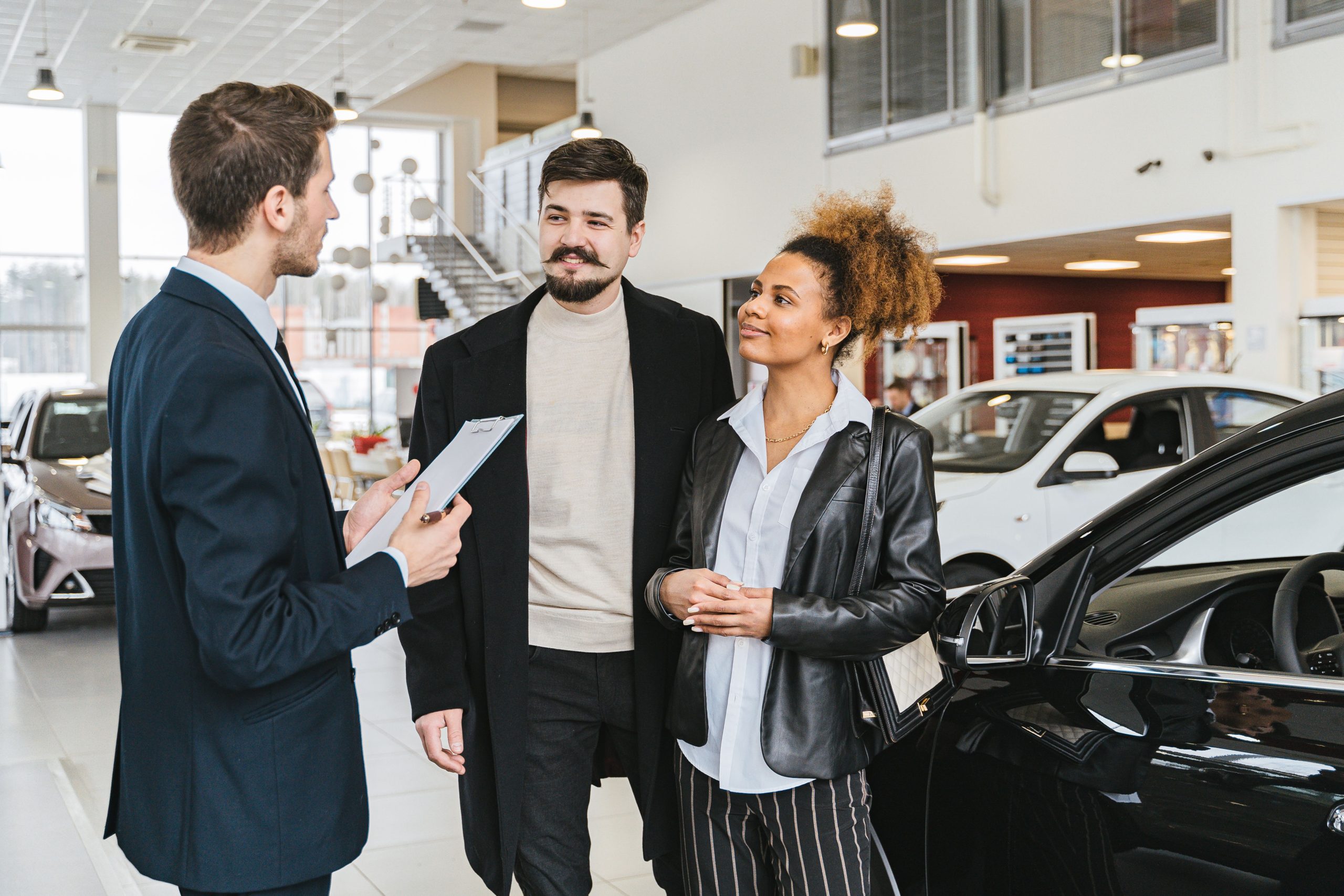 Couple discussing a car purchase with a salesman inside a dealership