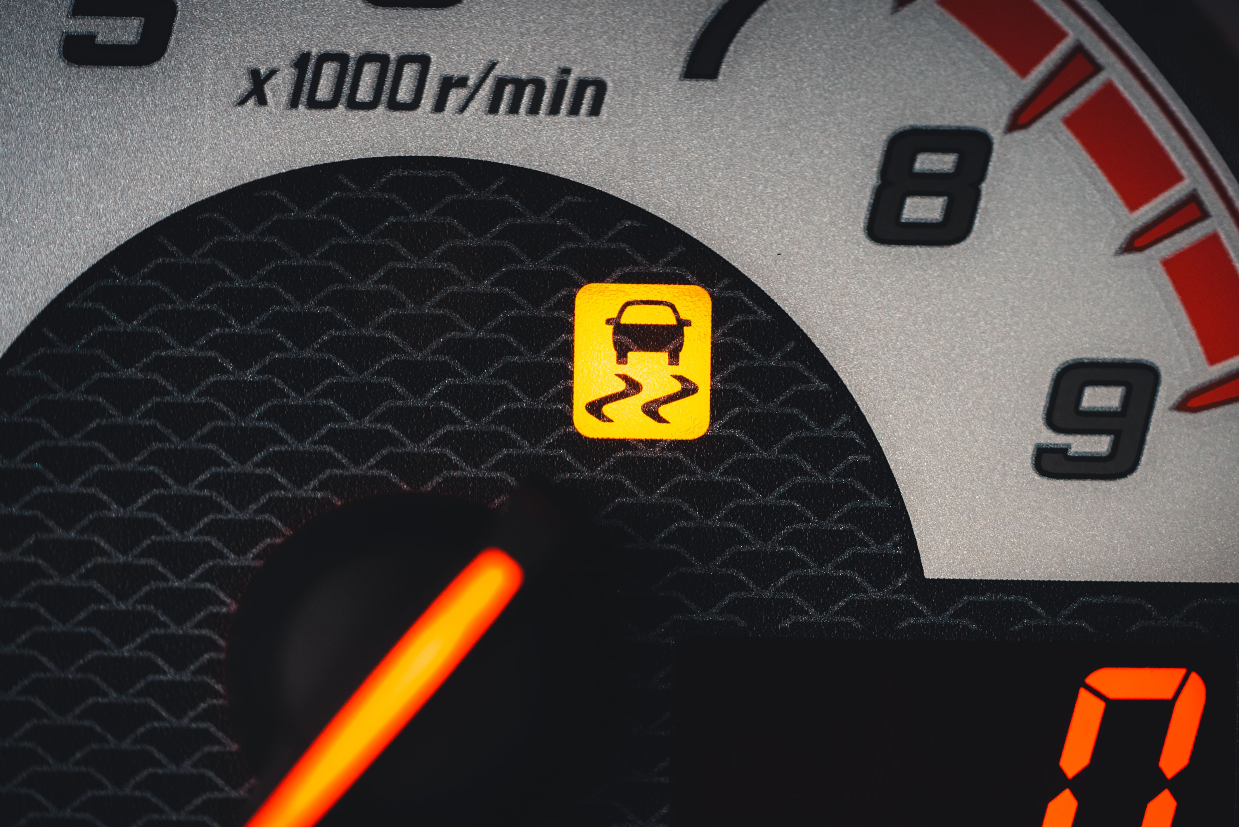 Close-up of a car dashboard showing a yellow traction control warning light